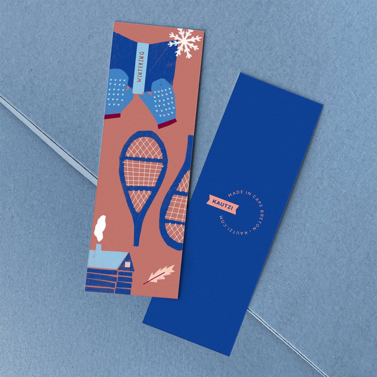 Wintering bookmark featuring blue snowshoes and mittens on coral background with white snowflakes, Kautzi Illustrations Bookmarks