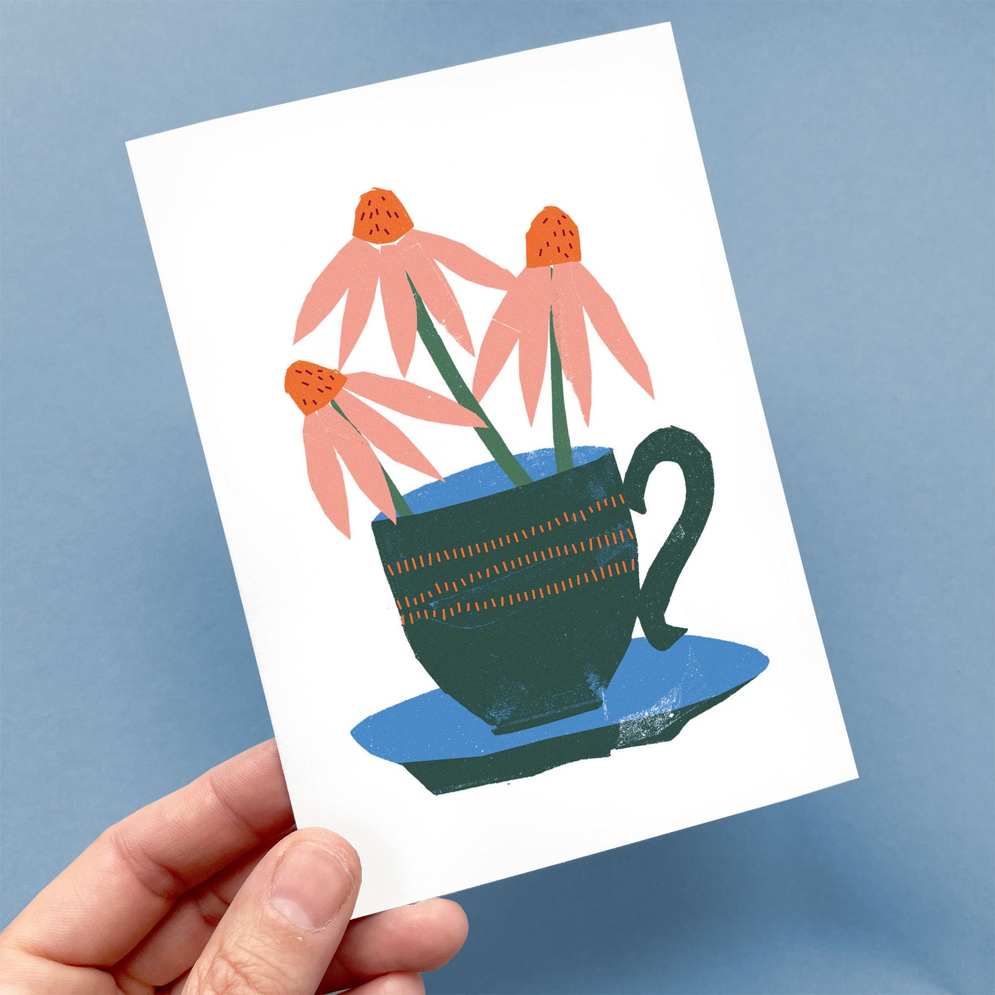 Greeting Card Coneflowers featuring pink echinacea blooms in a decorative dark green teacup with gold pattern on blue saucer