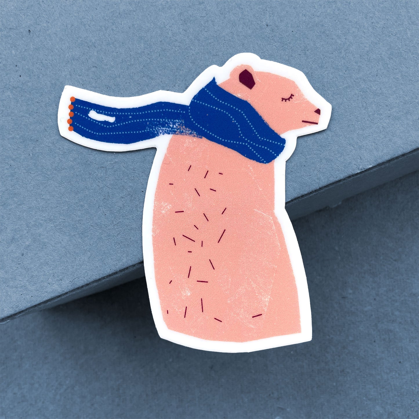 Sticker Bear vinyl decal featuring a pink bear wearing a cozy blue scarf, eyes closed in peaceful rest