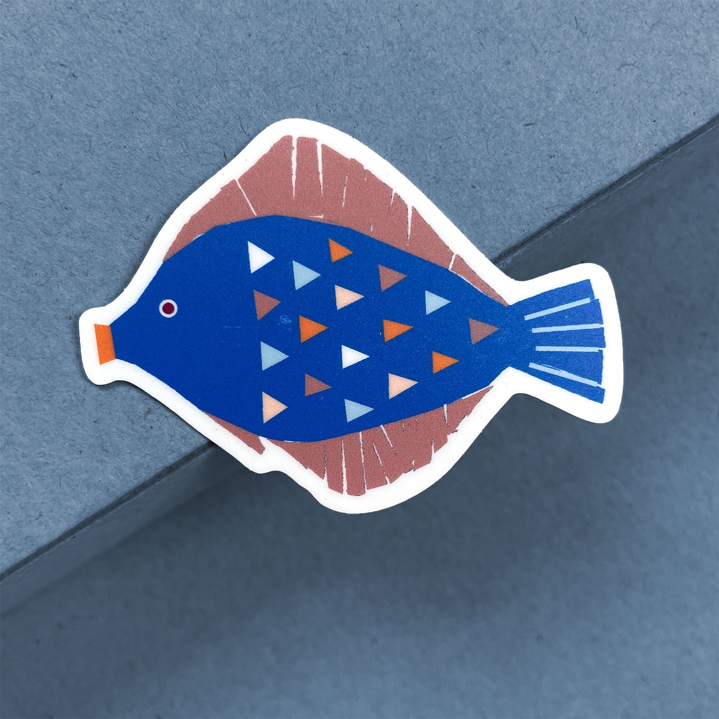 Sticker Flounder features a stylized blue and pink flatfish with geometric triangle patterns, illustrated in a modern design