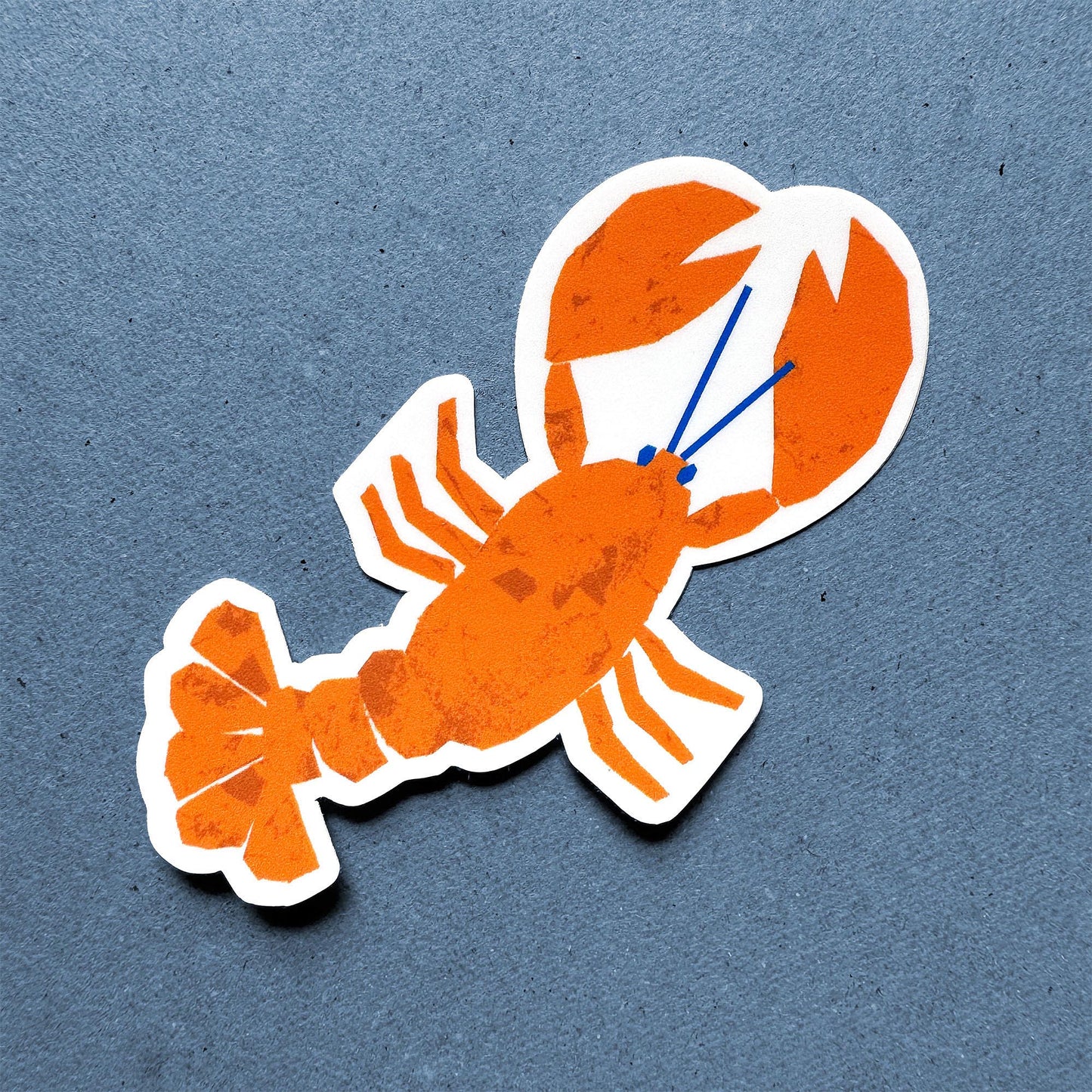 Bright orange lobster sticker with white border and blue accents on a custom-shaped vinyl design