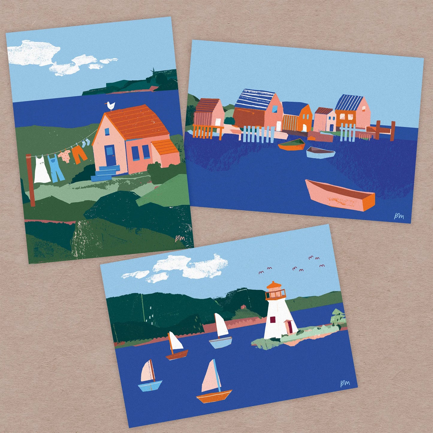 Kautzi Illustrations set of three 5x7 mini prints displayed on a kraft background, featuring a coastal house with a clothesline, a small fishing village, and the Kidston Island Lighthouse with sailboats. Inspired by coastal scenes from Cape Breton and the Maritimes, Canada.