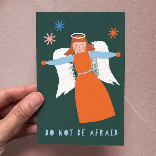 Handheld Christmas Card Angel with vibrant orange and blue illustration of an angel and text “Do Not Be Afraid” on dark green background.
