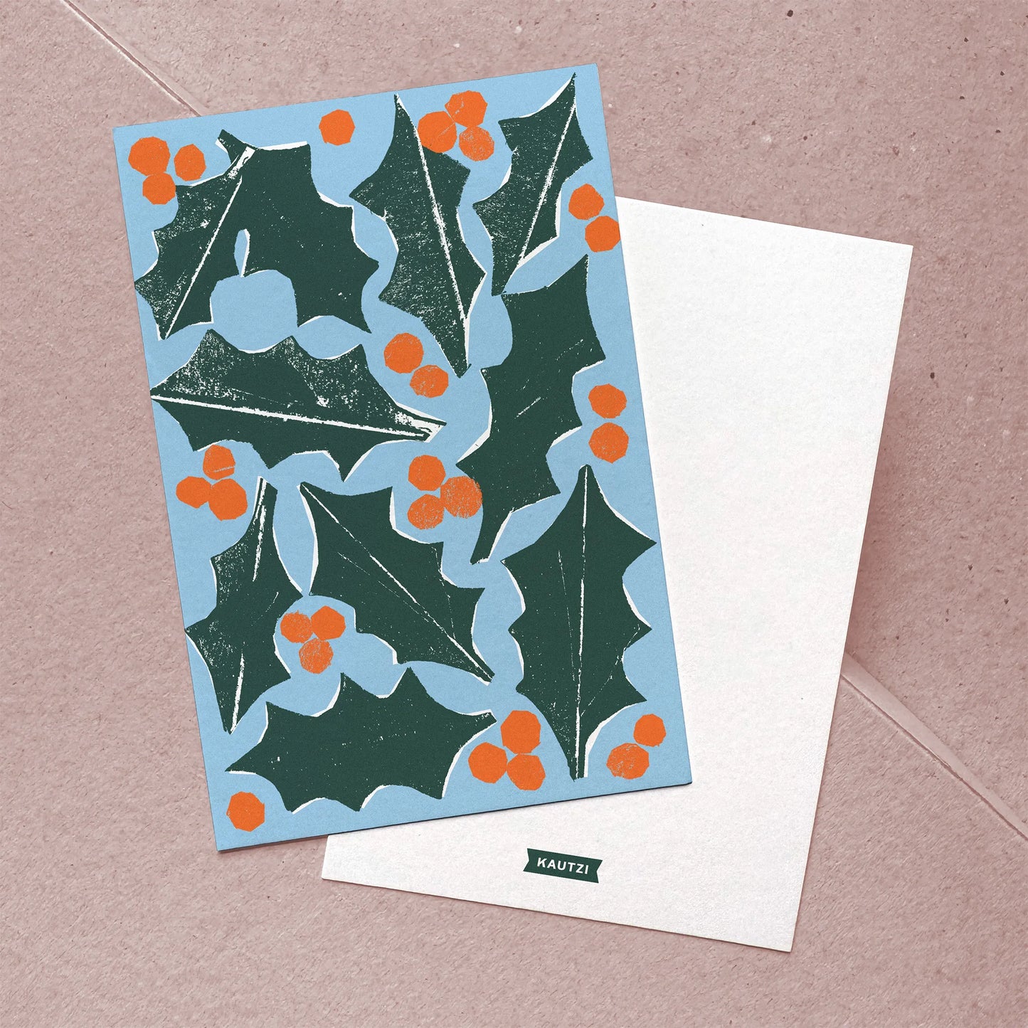 Front and back view of flat Christmas card featuring hand-cut holly and berries design and minimal logo back.
