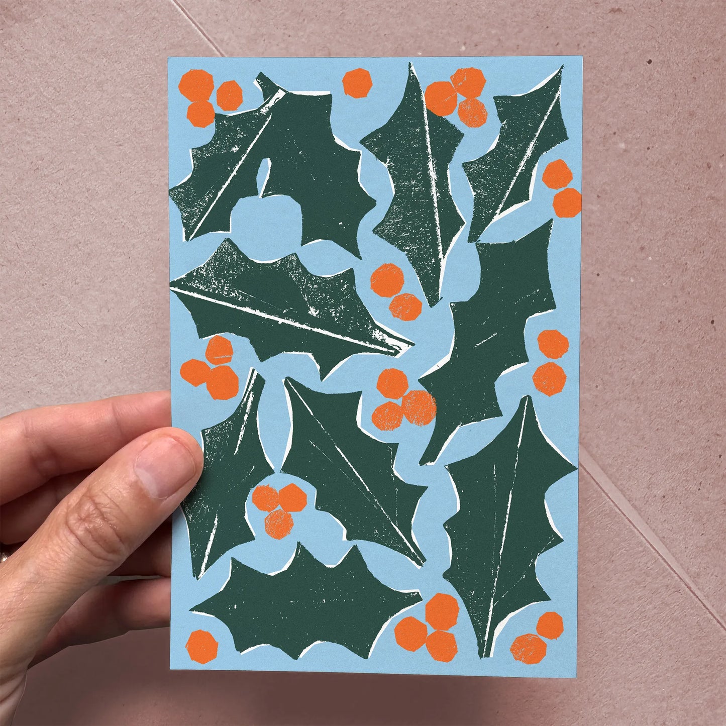 Hand holding “Holly & Berries” flat card, showing size and softly textured paper.