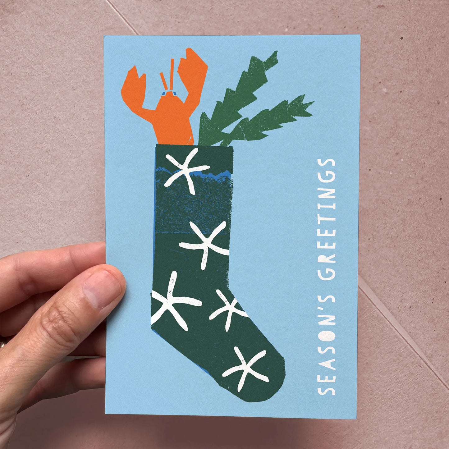 Hand holding the “Lobster Stocking” flat Christmas card to show size and paper texture.