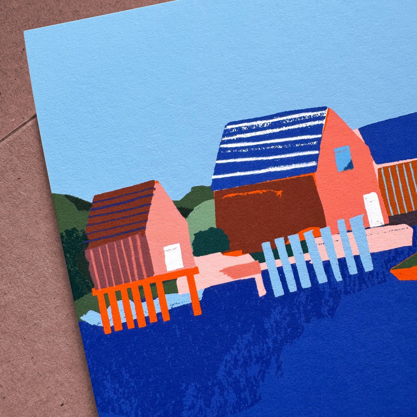 Close-up of a 5x7 art print showing colourful fish shacks and docks in a Nova Scotia harbour, highlighting the textured cotton paper and layered design.