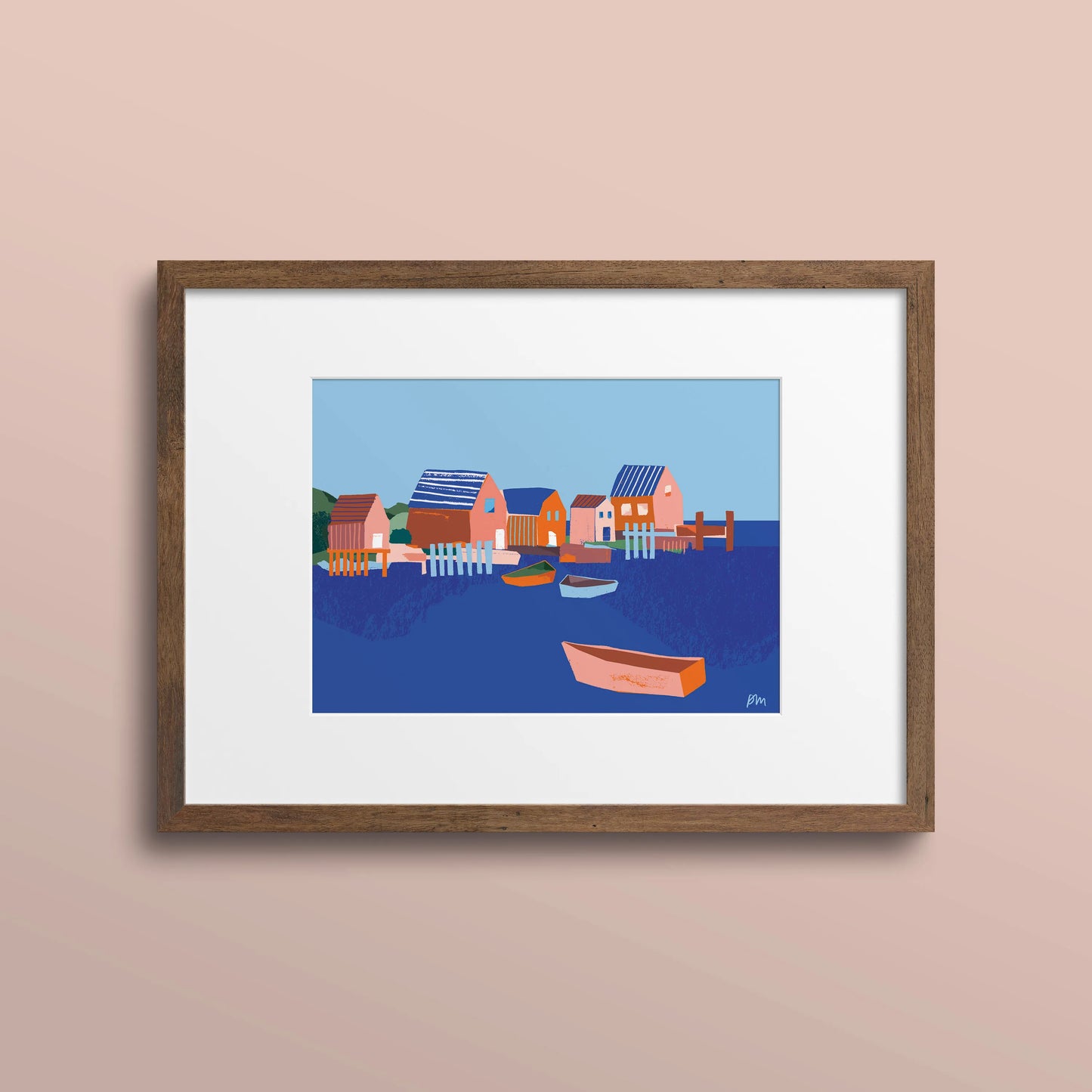 Framed 5x7 art print of colourful fish shacks and boats in a Nova Scotia harbour, shown with a white mat and wood frame on a pale pink wall.