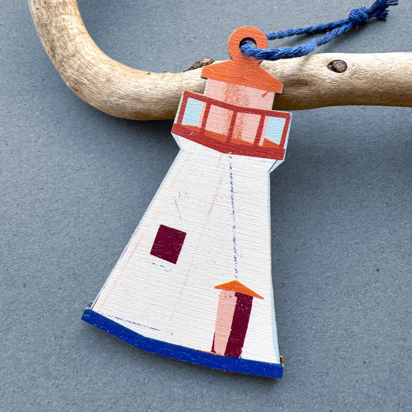 Kautzi wooden lighthouse ornament hanging from driftwood – illustrated Cape Breton, Nova Scotia lighthouse design in cream, red and blue with navy cord