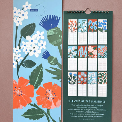 Two views of the 2026 “Flowers of the Maritimes” wall calendar by Kautzi. On the left, the front cover features bold cut-paper illustrations of pale pink mayflowers, red-orange wild roses, and a blue thistle on a sky blue background. On the right, the back side displays small previews of all 12 monthly pages, each with a unique floral illustration and lined space for writing. The background is deep green with text describing the calendar's features.
