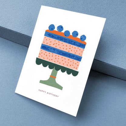 Greeting Card Birthday Cake illustrated with layered pink and blue cake topped with blueberries on green cake stand