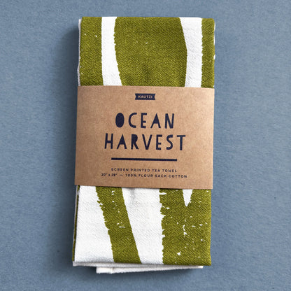 The Ocean Harvest tea towel by Kautzi, neatly folded and wrapped in kraft paper packaging with the product name and design details.