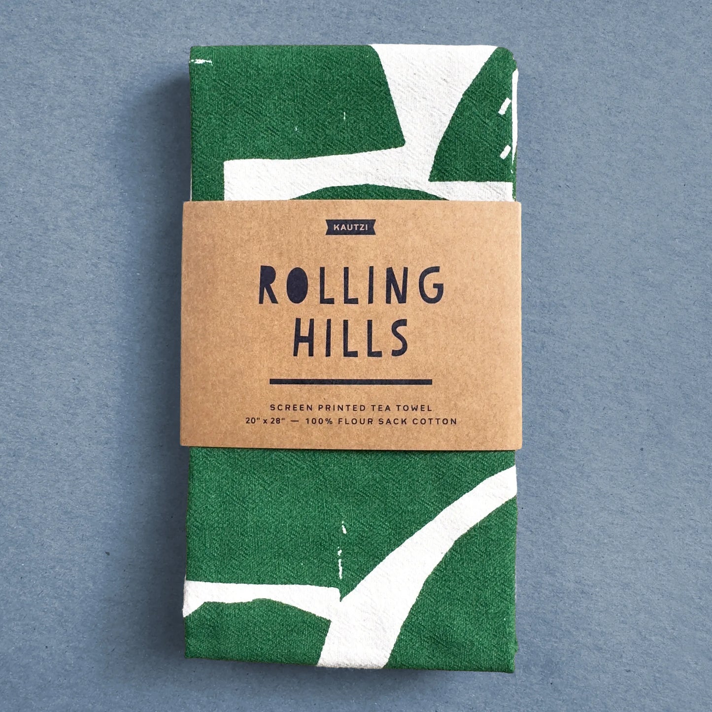 The Rolling Hills tea towel by Kautzi, neatly folded and wrapped in kraft paper packaging with the product name and description.