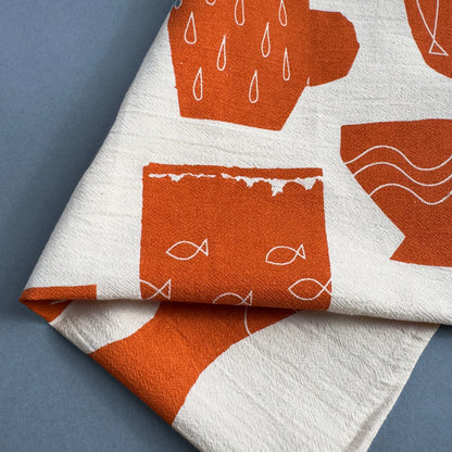 Close-up of the Seaside Dishes tea towel by Kautzi, featuring a bold terracotta and white pattern inspired by coastal ceramics, screen-printed on flour sack cotton.