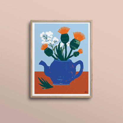 Kautzi Thistles & Teapot 11" × 14" print in light wood frame – still life illustration of thistles and baby’s breath in a blue teapot on a warm terracotta surface, designed and printed in Cape Breton, Nova Scotia.