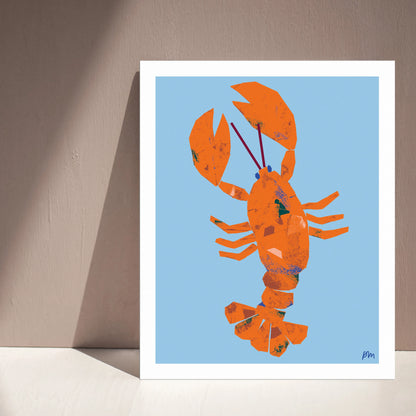 Kautzi Illustrations 8×10 Lobster art print leaning against a wall with natural light and shadows, featuring an orange lobster on a light blue background, inspired by East Coast and Maritime themes.