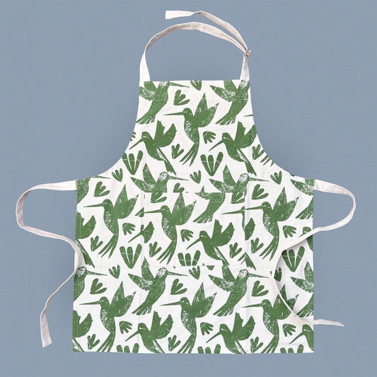 Kautzi Hummingbirds apron laid flat on a soft grey background, screen printed in green on natural cotton with an all-over hummingbird pattern, Cape Breton, Nova Scotia, Canada.