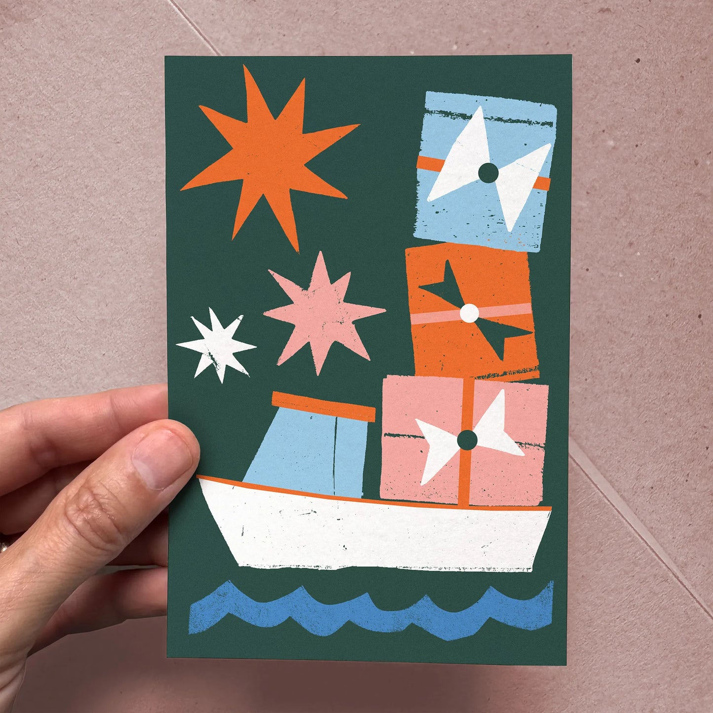 Hand holding the "Christmas Cargo" Christmas card, showing size and textured cotton paper finish.