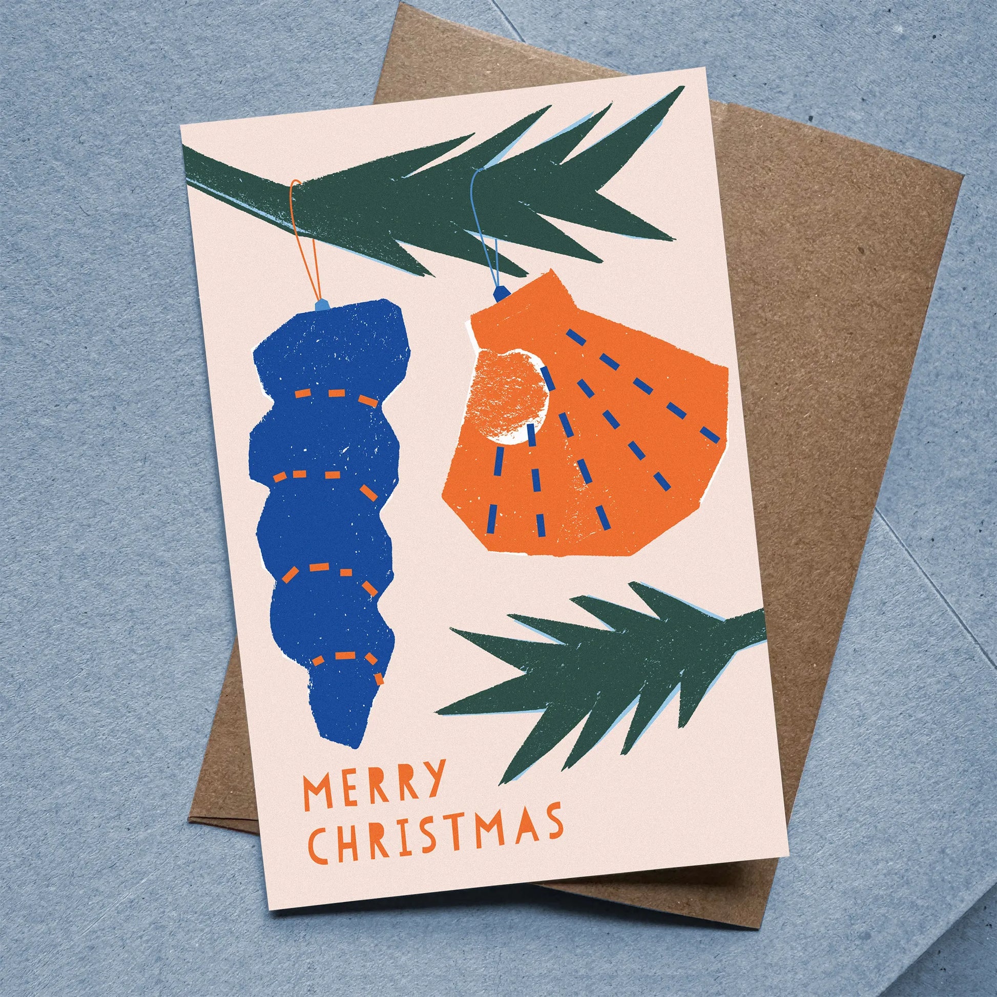 Flat Christmas card with seashell ornaments on pink background, paired with kraft envelope.