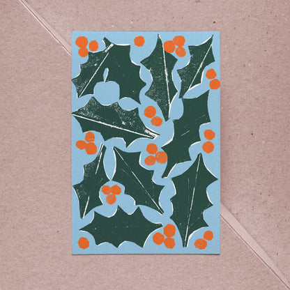 Full front view of holiday card showing holly leaves and orange berries in bold graphic style.
