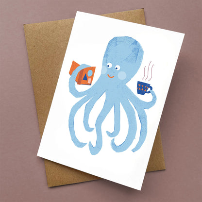 Kautzi greeting card showing a smiling blue octopus holding a cup and a book, paired with a kraft envelope – designed in Cape Breton, Nova Scotia.