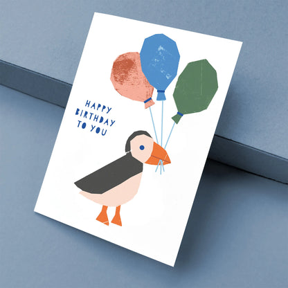 Kautzi birthday greeting card with puffin holding balloons, graphic illustration on white card, designed in Cape Breton, Nova Scotia, Canada