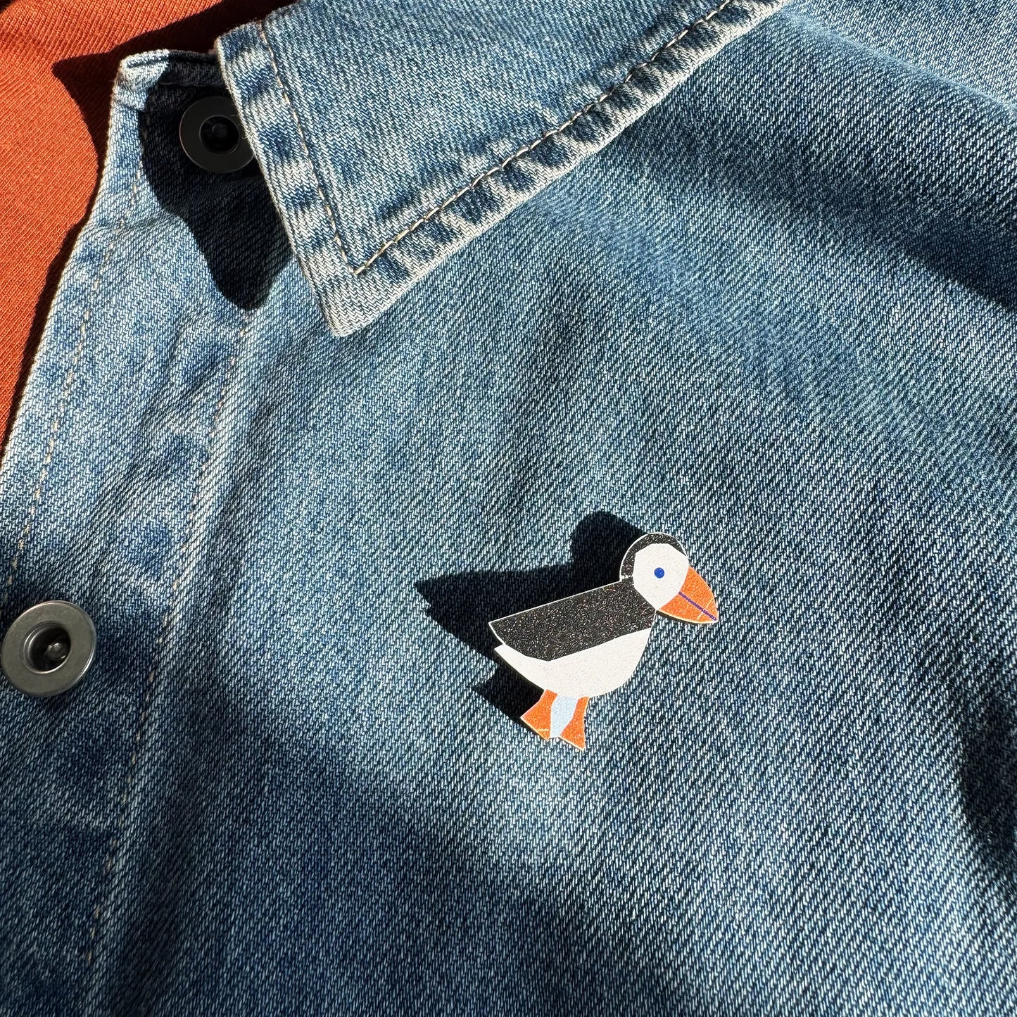 Kautzi maple wood veneer puffin pin badge attached to denim jacket, coastal wildlife accessory