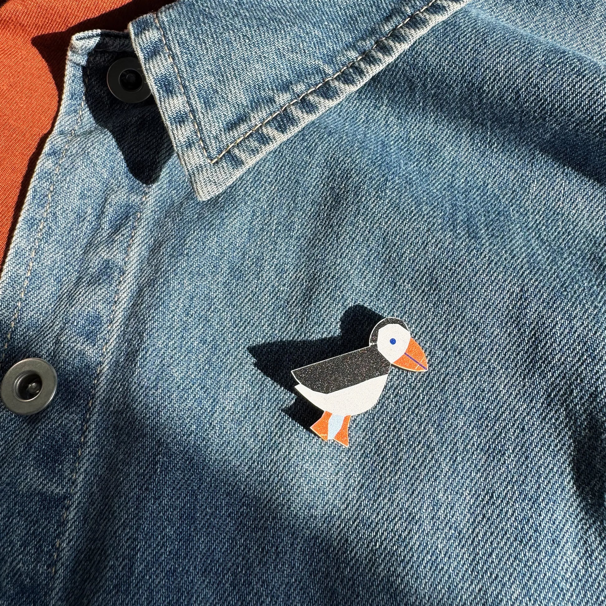 Kautzi maple wood veneer puffin pin badge attached to denim jacket, coastal wildlife accessory