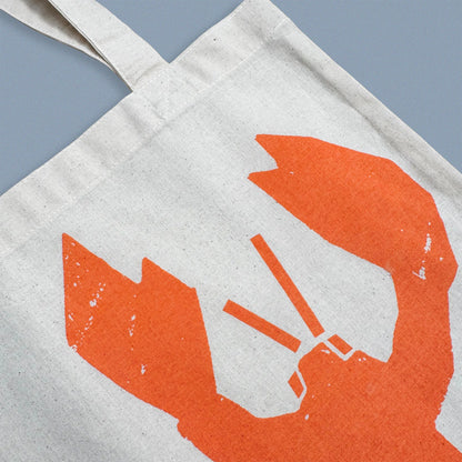 Detail of orange lobster illustration screen-printed on Kautzi cotton tote bag, showing fabric texture and print, Cape Breton, Nova Scotia, Canada.