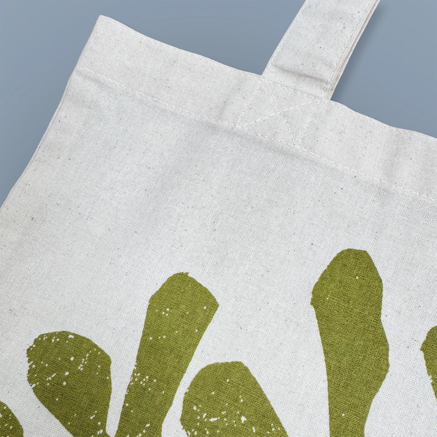 Detail of green rockweed illustration screen-printed on Kautzi cotton tote bag, showing fabric texture and print, Cape Breton, Nova Scotia, Canada.