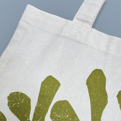 Detail of green rockweed illustration screen-printed on Kautzi cotton tote bag, showing fabric texture and print, Cape Breton, Nova Scotia, Canada.