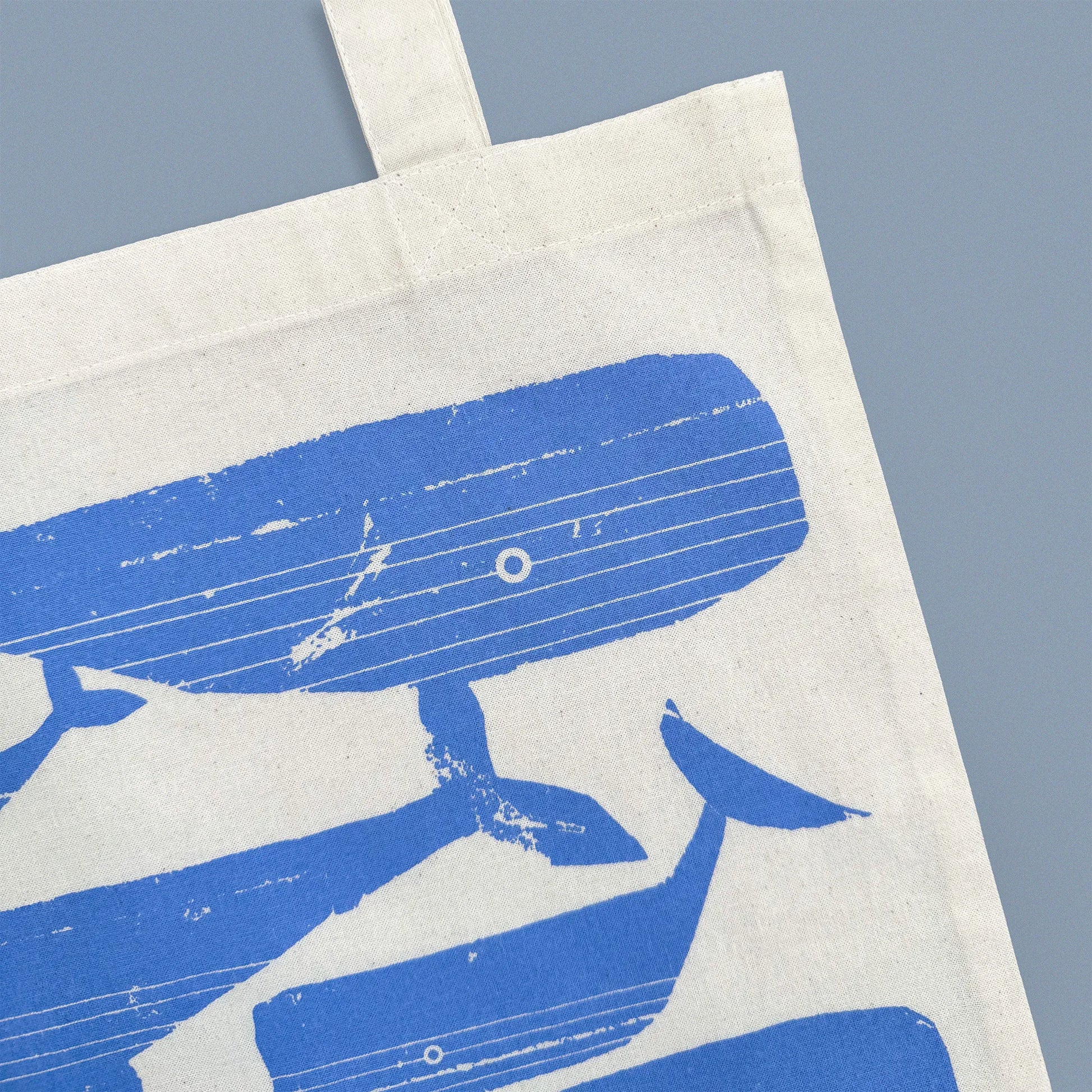 Detail of blue whale illustration screen-printed on Kautzi cotton tote bag, showing fabric texture and print, Cape Breton, Nova Scotia, Canada.