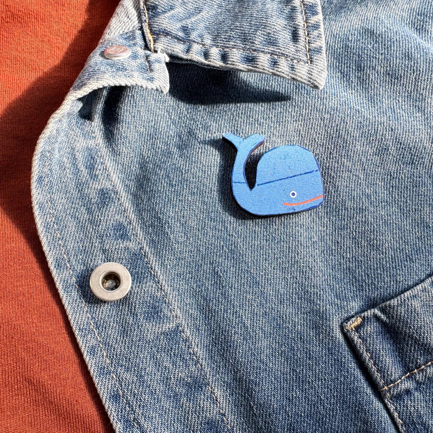 Kautzi maple wood veneer whale pin badge attached to denim jacket, playful maritime accessory