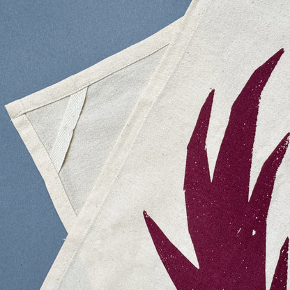 Kautzi Wild Thistles tea towel corner with hanging loop and deep plum thistle motif screen printed on natural cotton.